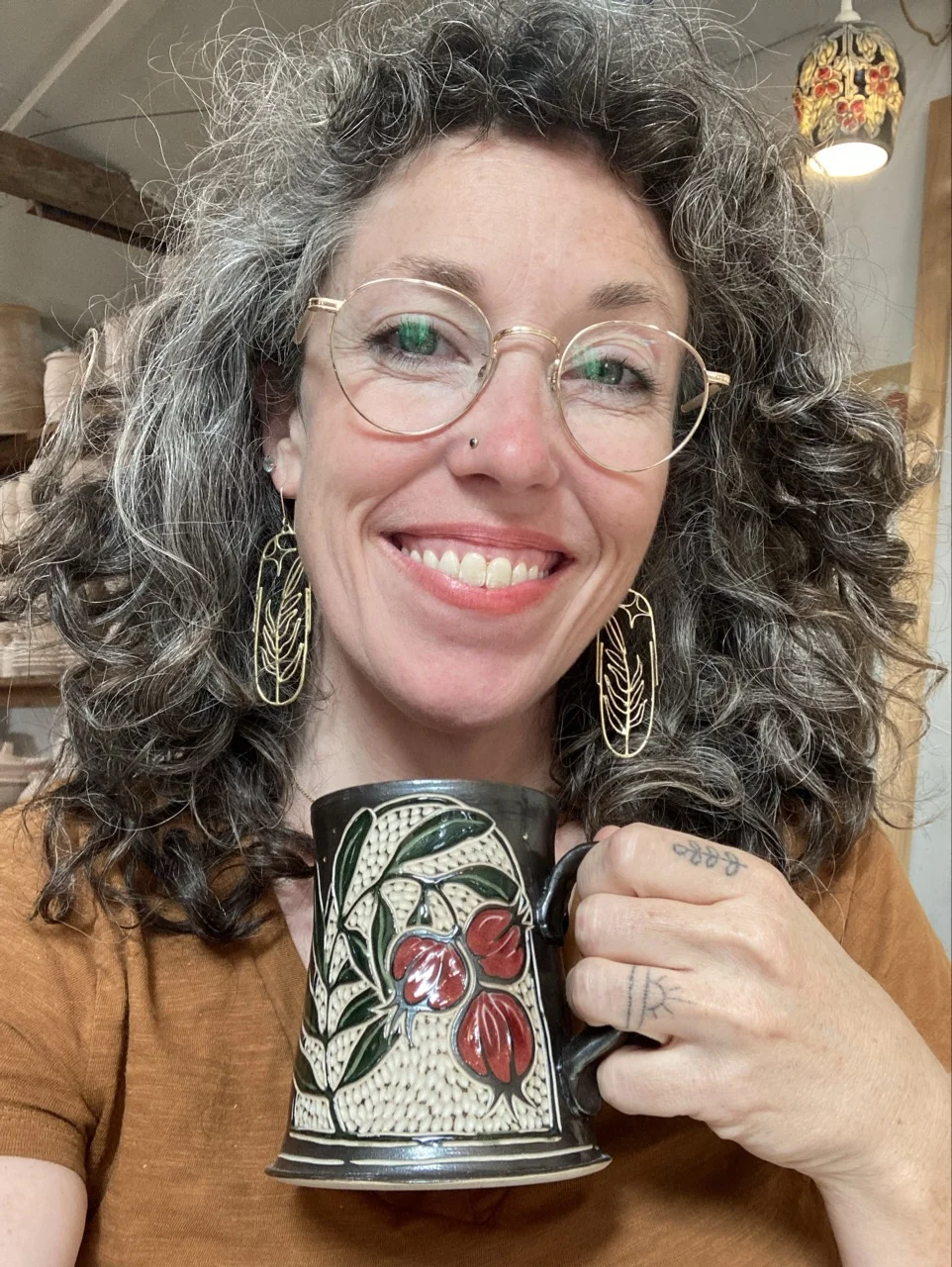 Erica holding a pomegranate mug in her typical painted and carved style