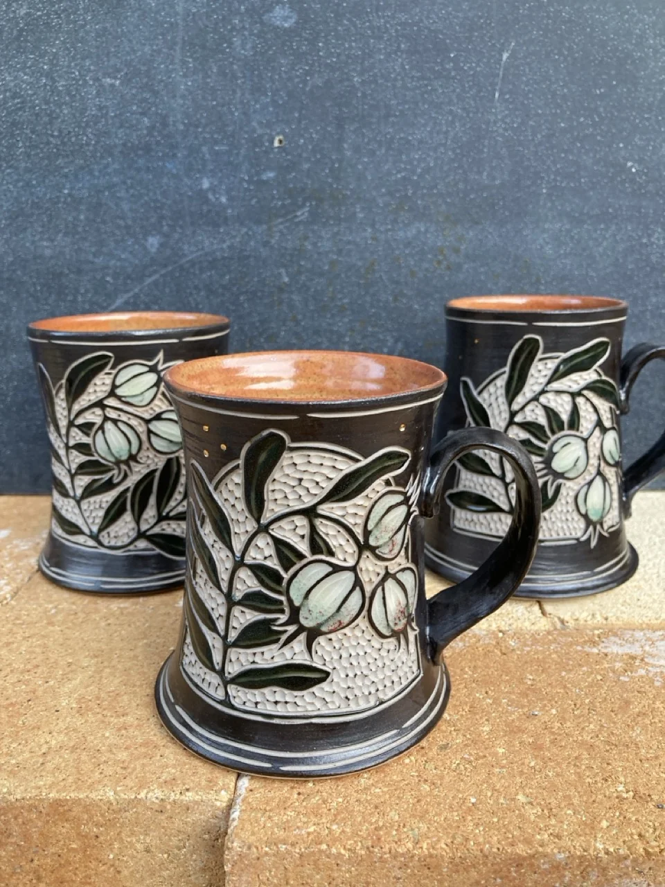 Three mugs with seed pod decorations