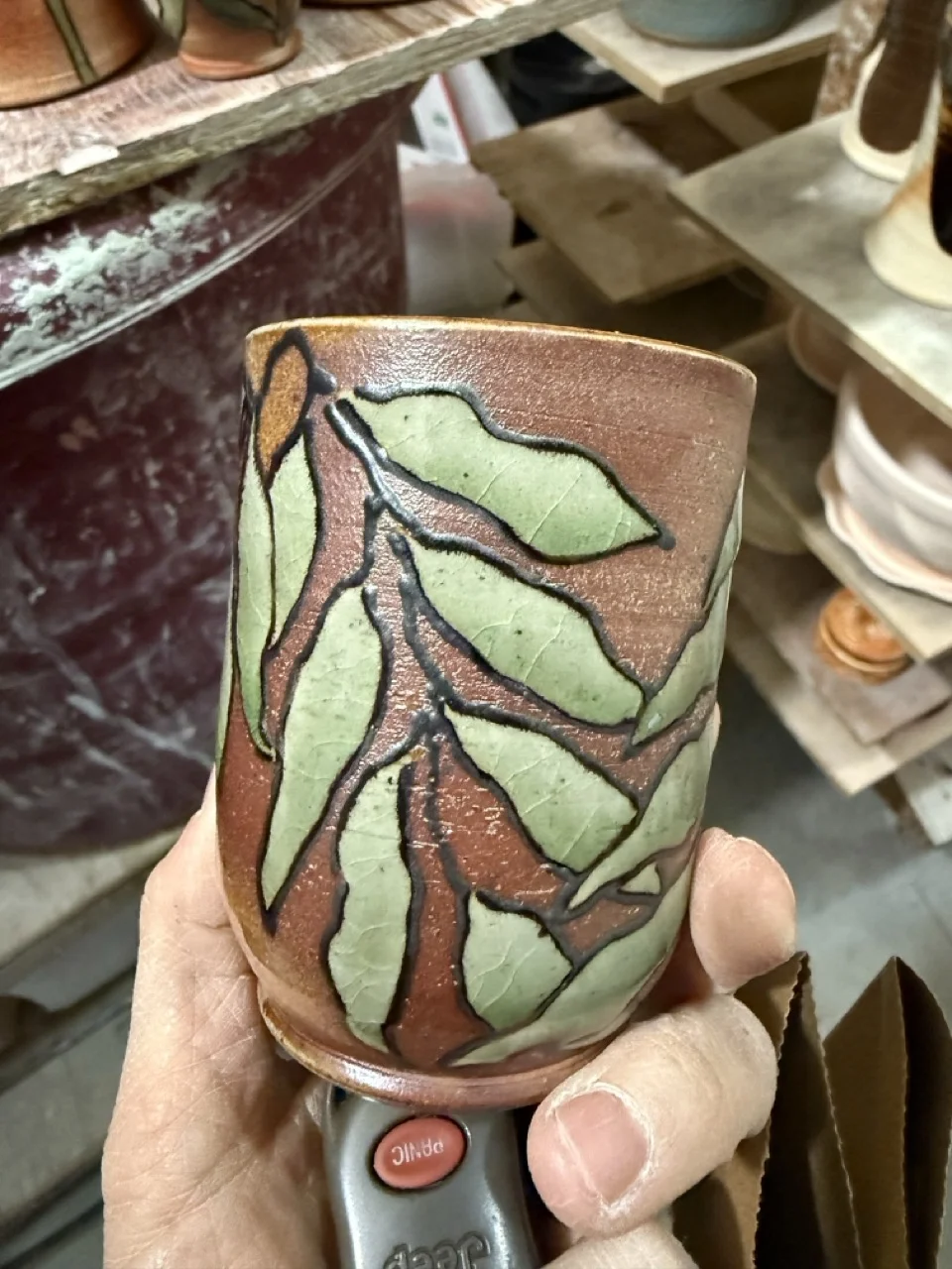 Small brown cup with light green leaf decoration